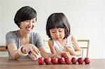 Mother and daughter with red apples in a row