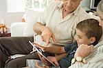 Grandparents sitting with grandson and looking at digital tablet