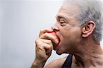 Senior man eating apple, close up