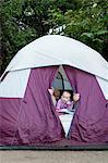 Toddler twins and father peeking out of tent