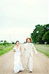 Portrait of couple on wedding day running on dirt track