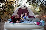 Toddler twins on camping mattress with father