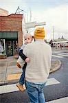 Father carrying young son across pedestrian crossing