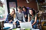 Group of people gathered around computer in cafe