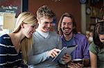 Group of people gathered around digital tablet in cafe