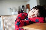 Boy in pyjamas resting on elbows on table