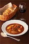 Still life of casserole in bowl with red wine and bread