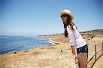 Young woman standing on fence, Palos Verdes, California, USA