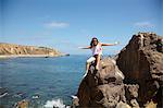 Young woman sitting on rocks, Palos Verdes, California, USA