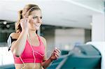 Young woman with smartphone armband and earplugs