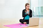 Young woman on yoga mat with mug of tea