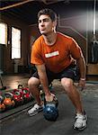 Bodybuilder lifting kettlebells in gym