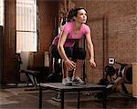 Young woman jumping on table in gym