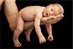 Newborn boy lying on his dad's arm over black background