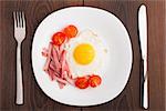 Fried egg with ham and tomato on a plate