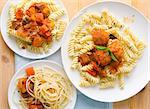 plate of spaghetti with meatballs in tomato marinara sauce and ingredients on a wooden table