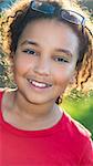 Outdoor portrait of a beautiful young mixed race interracial African American girl child smiling backlit in sunshine with glasses on her head