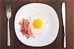 Fried egg with ham on a white plate