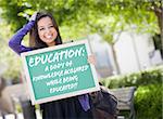 Excited Mixed Race Female Student Holding Chalkboard With Education and the Definition Written on it.