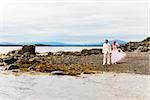 The groom in white suit and the bride in a pink dress on nature