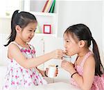 Eating yogurt. Happy Asian children eating yoghurt at home. Beautiful sisters . Healthcare concept.