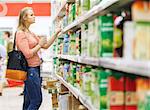 Young woman shopping for juice in produce department of a supermarket