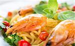 Pasta with shrimps, pepper and leafy greens close-up