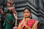 Beautiful young Indian woman in traditional sari dress praying in a hindu temple.