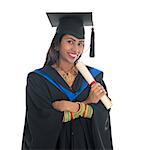 Happy Indian college student in graduation gown and cap holding diploma certificate. Portrait of mixed race Asian Indian and African American female model standing isolated on white background.
