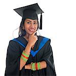 Happy Indian university student in graduation gown and cap thinking. Portrait of mixed race Asian Indian and African American female model standing isolated on white background.