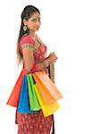 Portrait of beautiful young Indian woman shopper in traditional sari dress, standing isolated on white background.