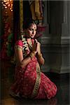 Young Indian woman in traditional sari dress praying in a hindu temple.