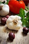 Food ingredinets. Garlic, olives, tomato and basil on wooden table.