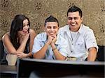 Young Latino family enjoying television indoors together