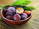 ripe purple plums on a wooden table