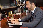 Focused businessman working on his laptop in a classy bar