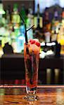 Close up on colourful cocktail with strawberries on the edge in a classy bar