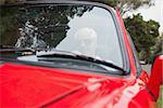 Handsome man driving red convertible on a bright day