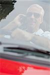 Cheerful handsome man in red convertible having phone call while driving