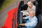 High angle view of smiling mature man having a ride with his wife in red convertible