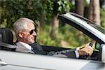 Relaxed businessman driving classy cabriolet on sunny day