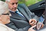 Partners working together on tablet in classy convertible on a bright day