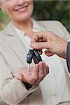 Close up on smiling businesswoman being given keys by her partner