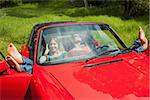 Cheerful young couple relaxing in classy cabriolet on a sunny day