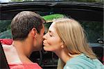 Attractive blonde kissing her boyfriend in classy convertible