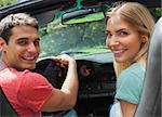 Cheerful couple looking at camera over shoulder while having a ride in cabriolet