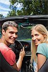 Smiling couple looking over shoulder at camera while having a ride in cabriolet