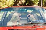 Loving couple in their red cabriolet having a ride on sunny day