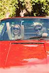 Loving couple having fun in their red cabriolet on a sunny day