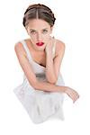 Woman sitting and looking at camera against white background